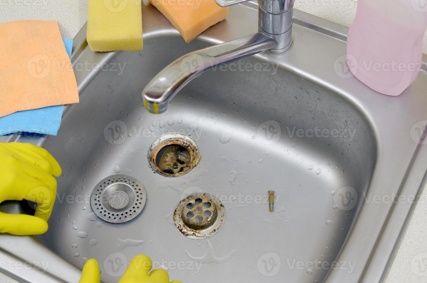 Silvery kitchen sink with a disassembled protective filter during the repair process photo