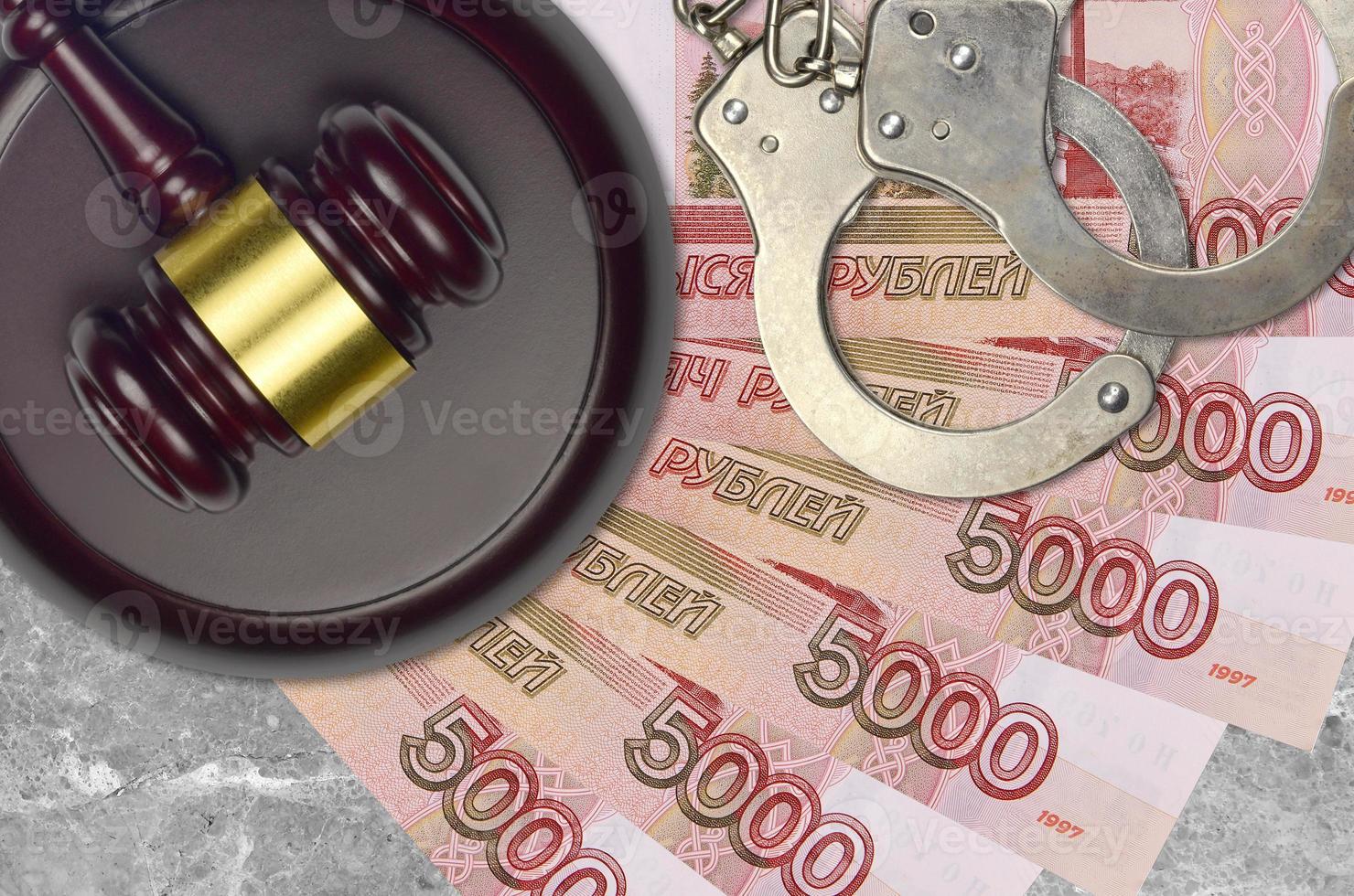 5000 russian rubles bills and judge hammer with police handcuffs on court desk. Concept of judicial trial or bribery. Tax avoidance photo