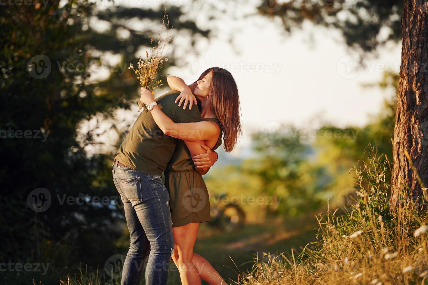 Lovely people embracing each other. Beautiful young couple have a good time in the forest at daytime photo