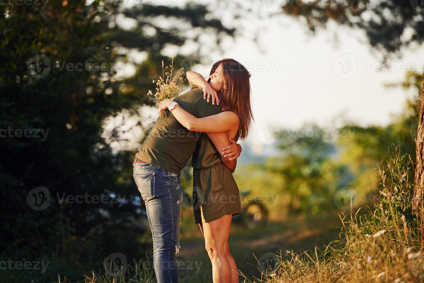 gente encantadora abrazándose unos a otros. hermosa pareja joven diviértete en el bosque durante el día foto