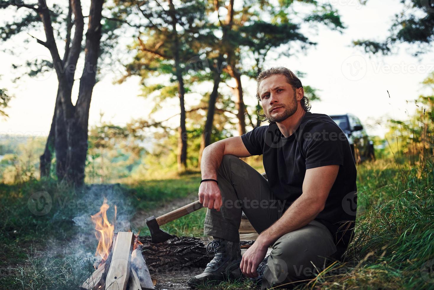 Time for a rest. Man in black shirt near the campfire in the forest at his weekend time photo