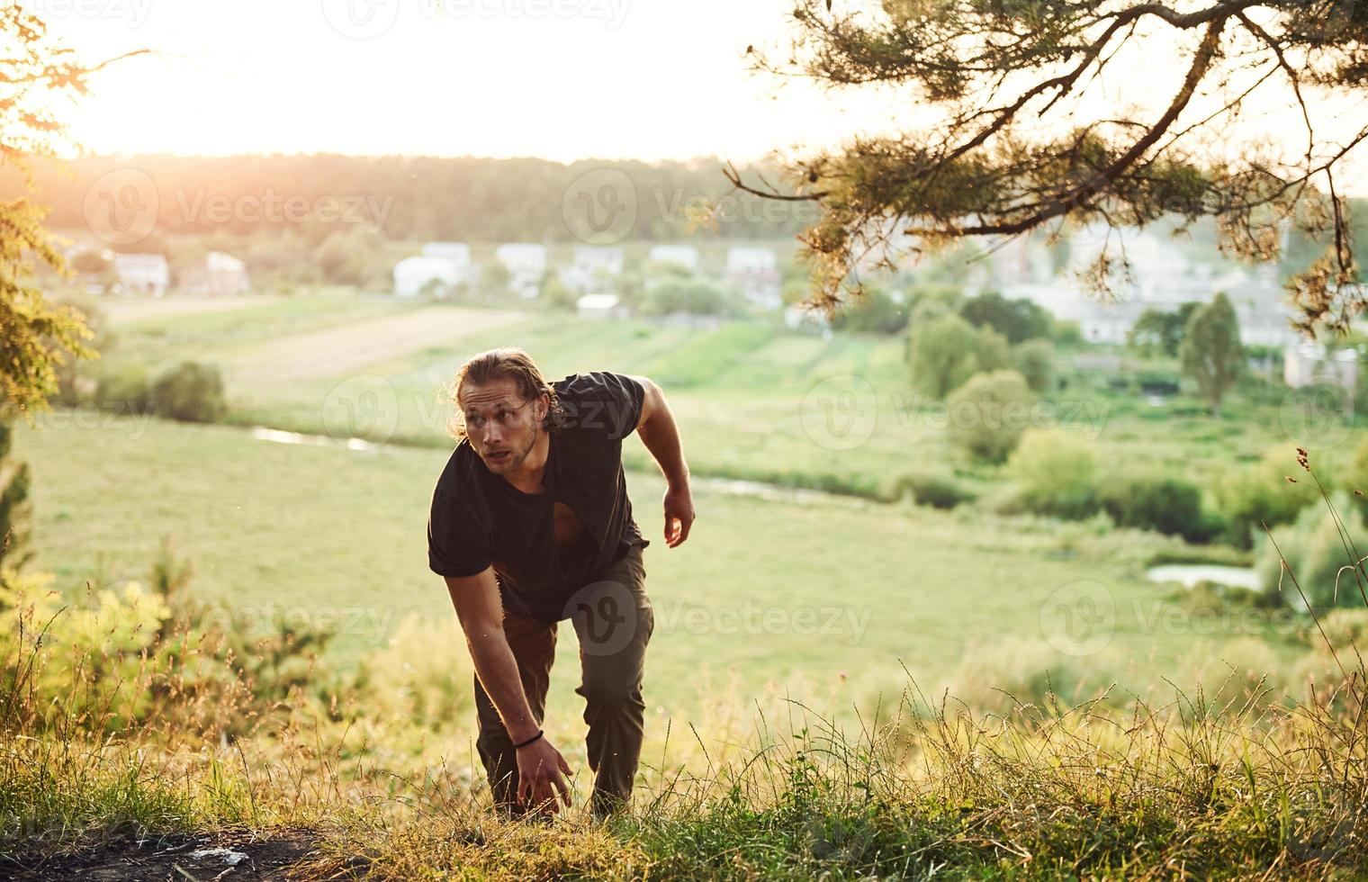 Conquesting that hill. Rural scene. Handsome man with muscular body type is in the forest at daytime photo