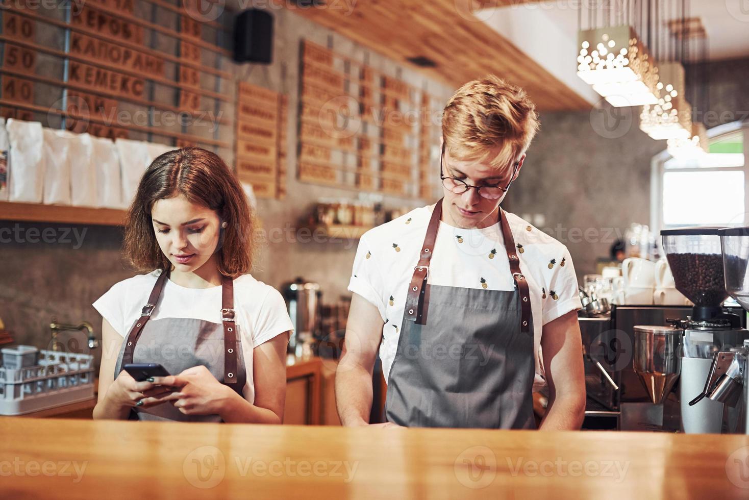Front view. Two young cafe workers indoors. Conception of business and