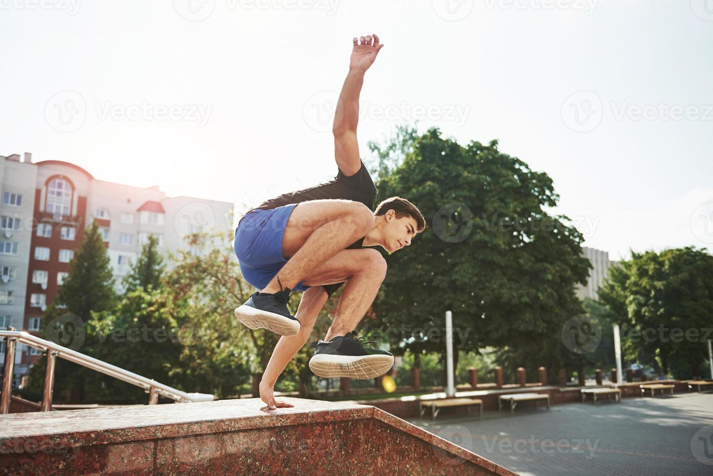 Natural lighting. Young sports man doing parkour in the city at sunny daytime photo