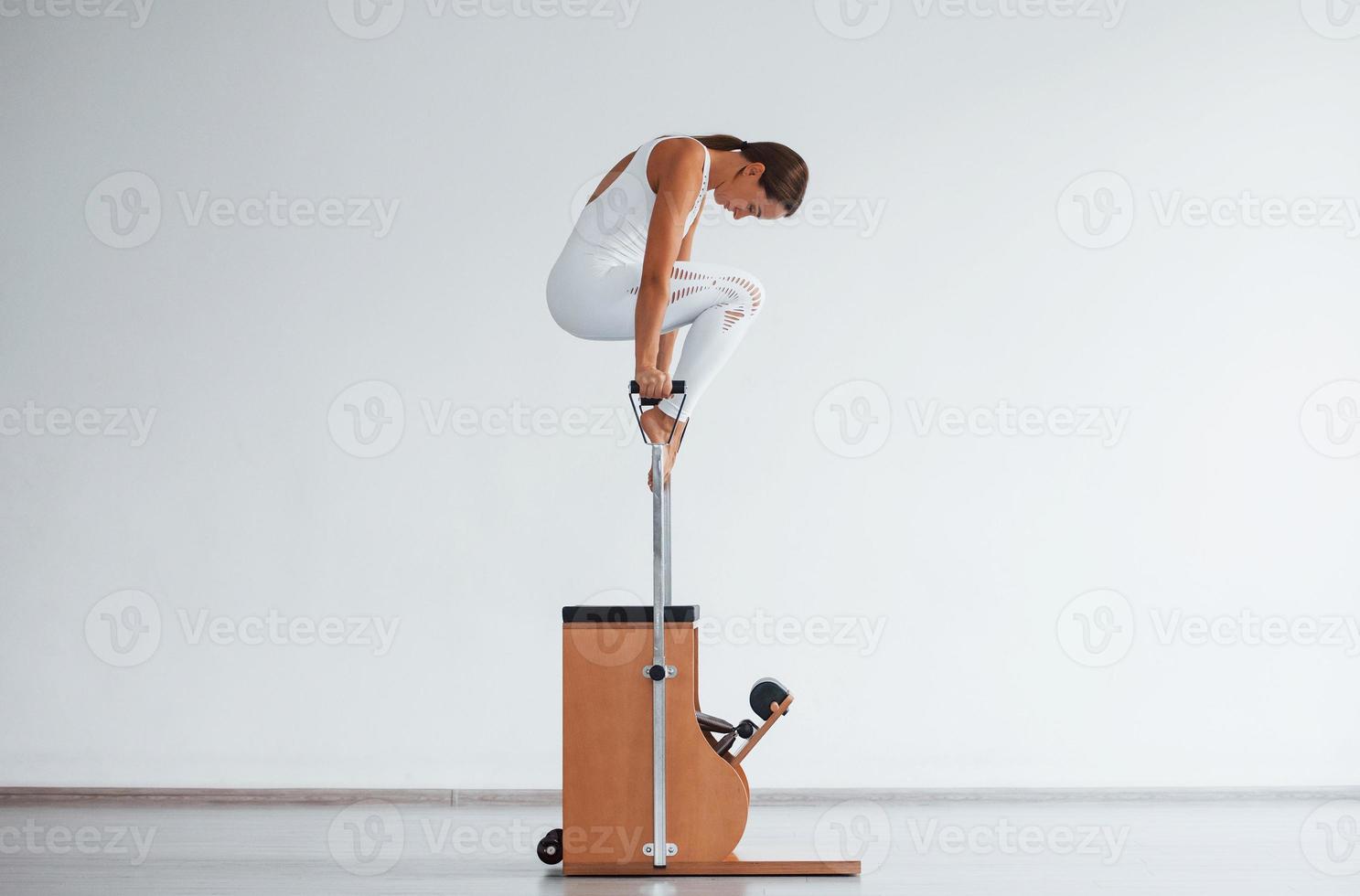 Confident young sporty woman with slim body type in the healthy center doing exercises by using special equipment photo