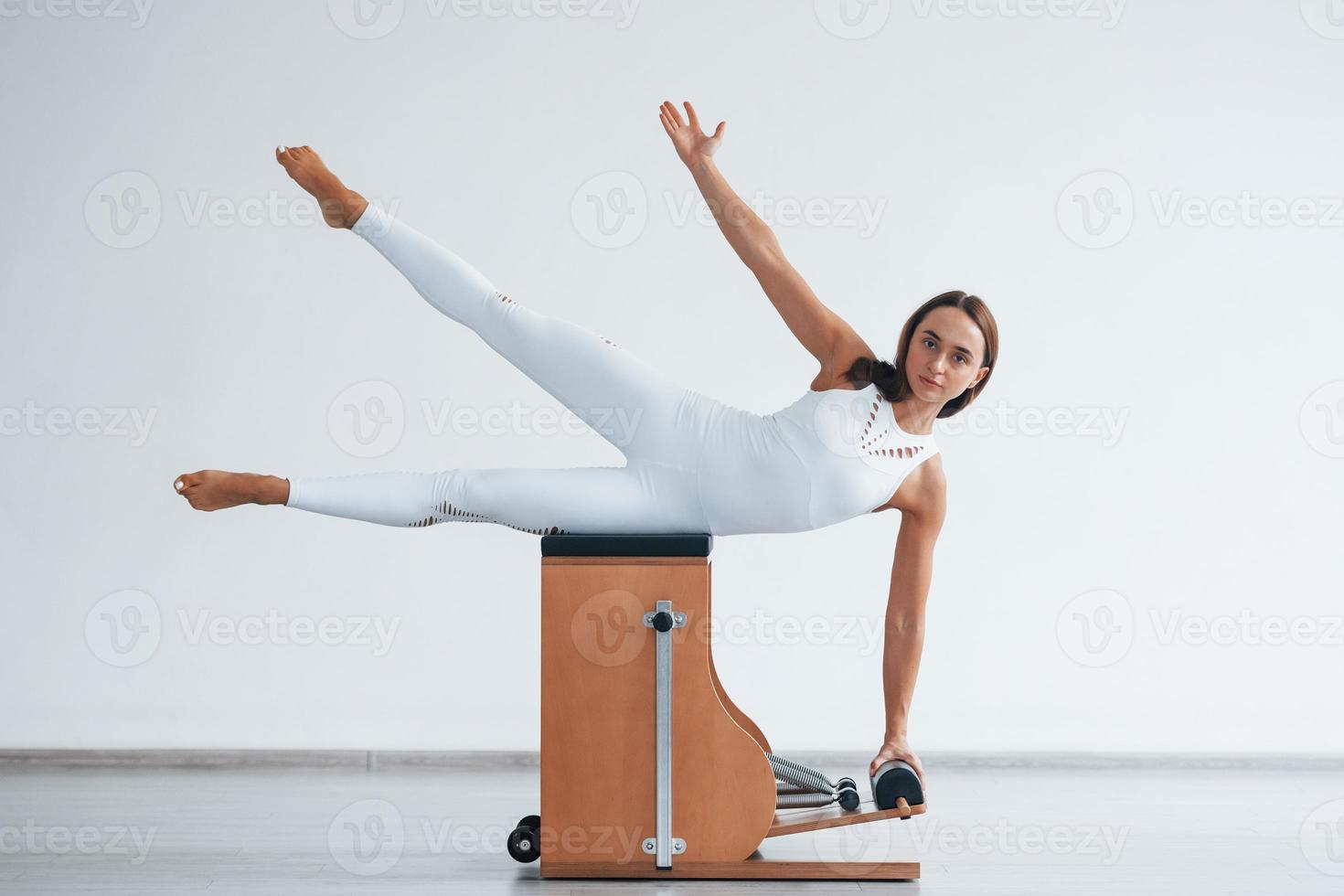 apoyándose en el costado. joven deportista segura de sí misma con un tipo de cuerpo delgado en el centro saludable haciendo ejercicios usando equipo especial foto