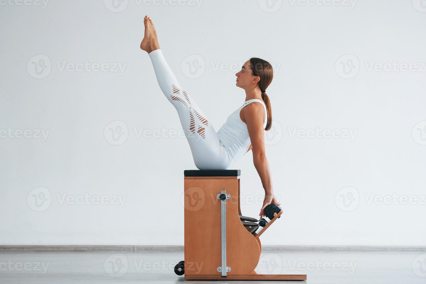Confident young sporty woman with slim body type in the healthy center doing exercises by using special equipment photo