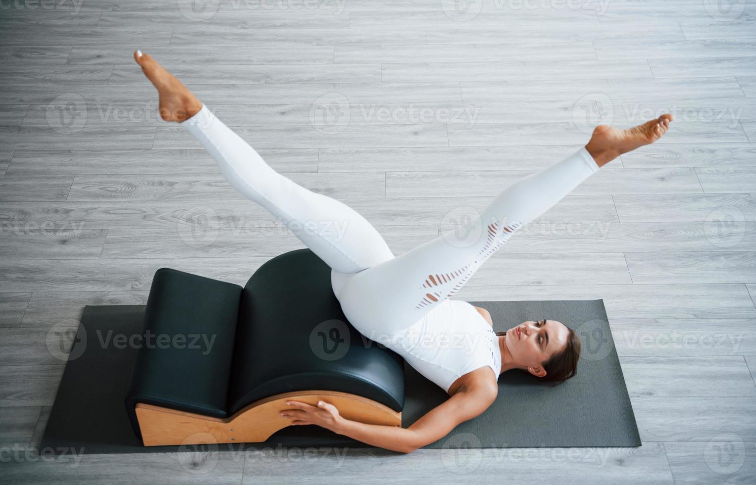 For the legs. Confident young sporty woman with slim body type in the healthy center doing exercises by using special equipment photo