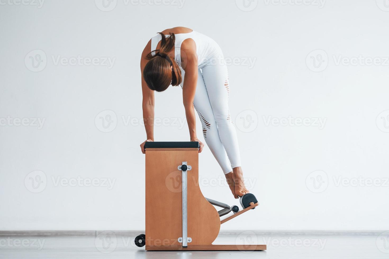 Confident young sporty woman with slim body type in the healthy center doing exercises by using special equipment photo