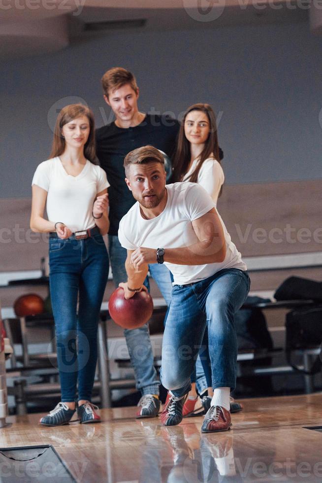 Front view. Young cheerful friends have fun in bowling club at their weekends photo