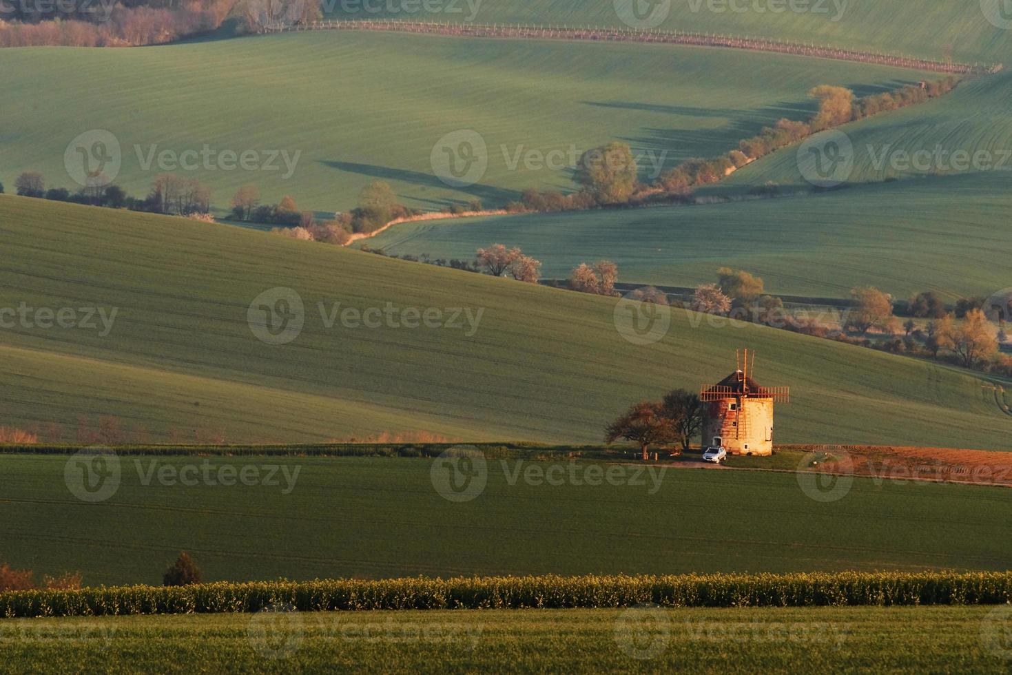 majestuoso paisaje de campo por la noche. molino de viento en el centro del prado foto