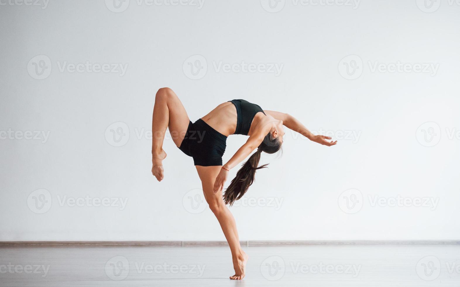 Full length photo. Young sporty woman in black clothes with slim body type in the healthy center doing exercises photo