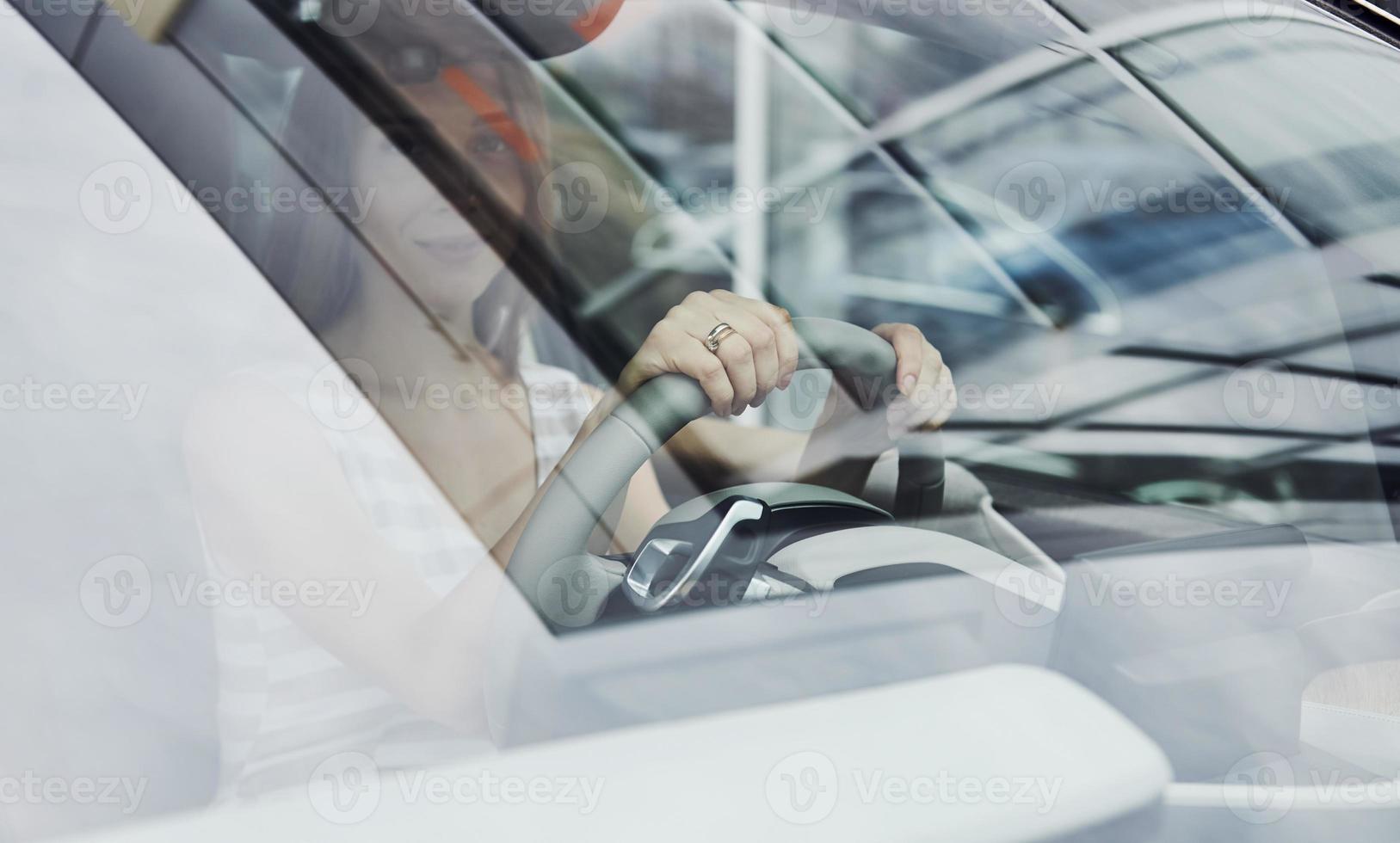 Front view. Reflection in the glass. Female driver inside of modern automobile. Testing brand new car photo
