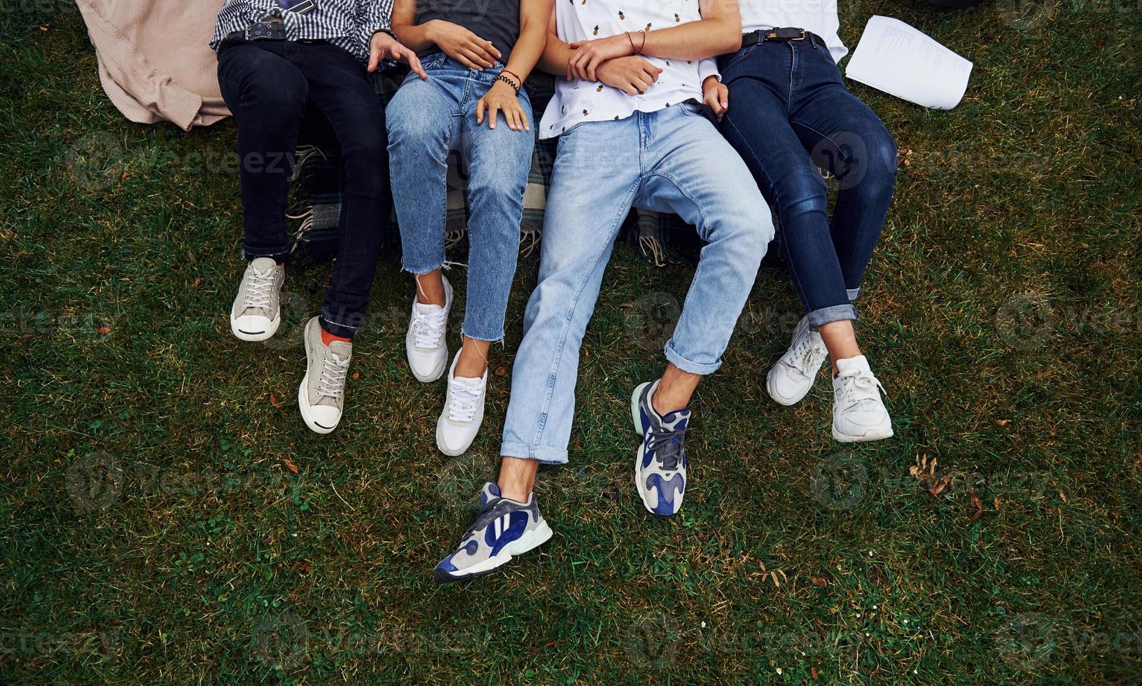Particle view. Group of young students in casual clothes on green grass at daytime photo