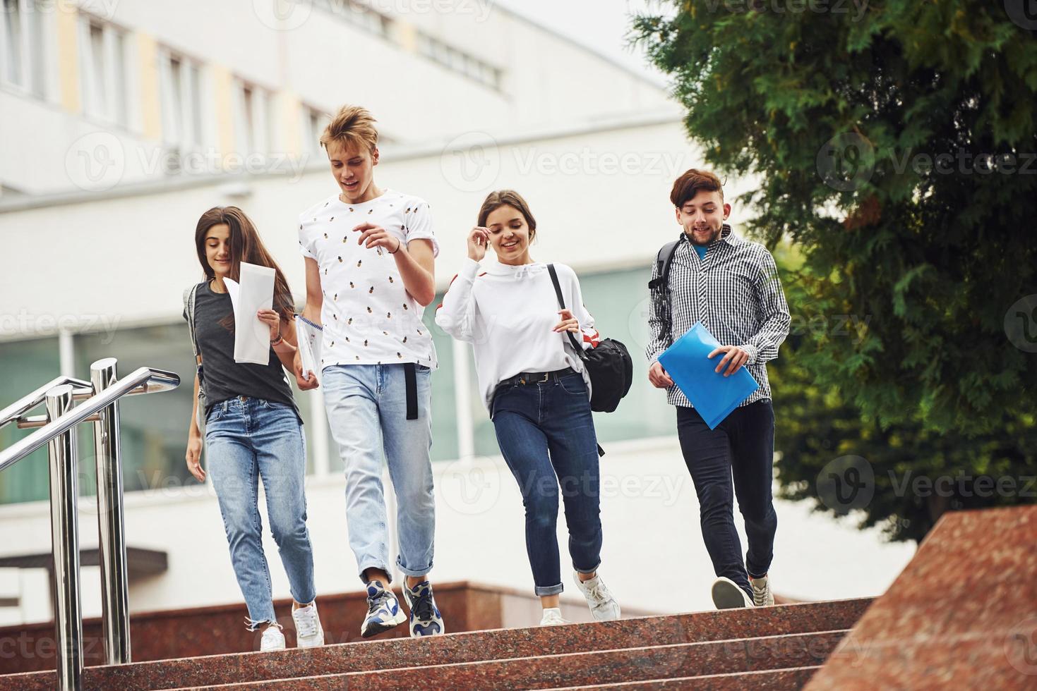caminando por las escaleras. grupo de jóvenes estudiantes con ropa informal cerca de la universidad durante el día foto