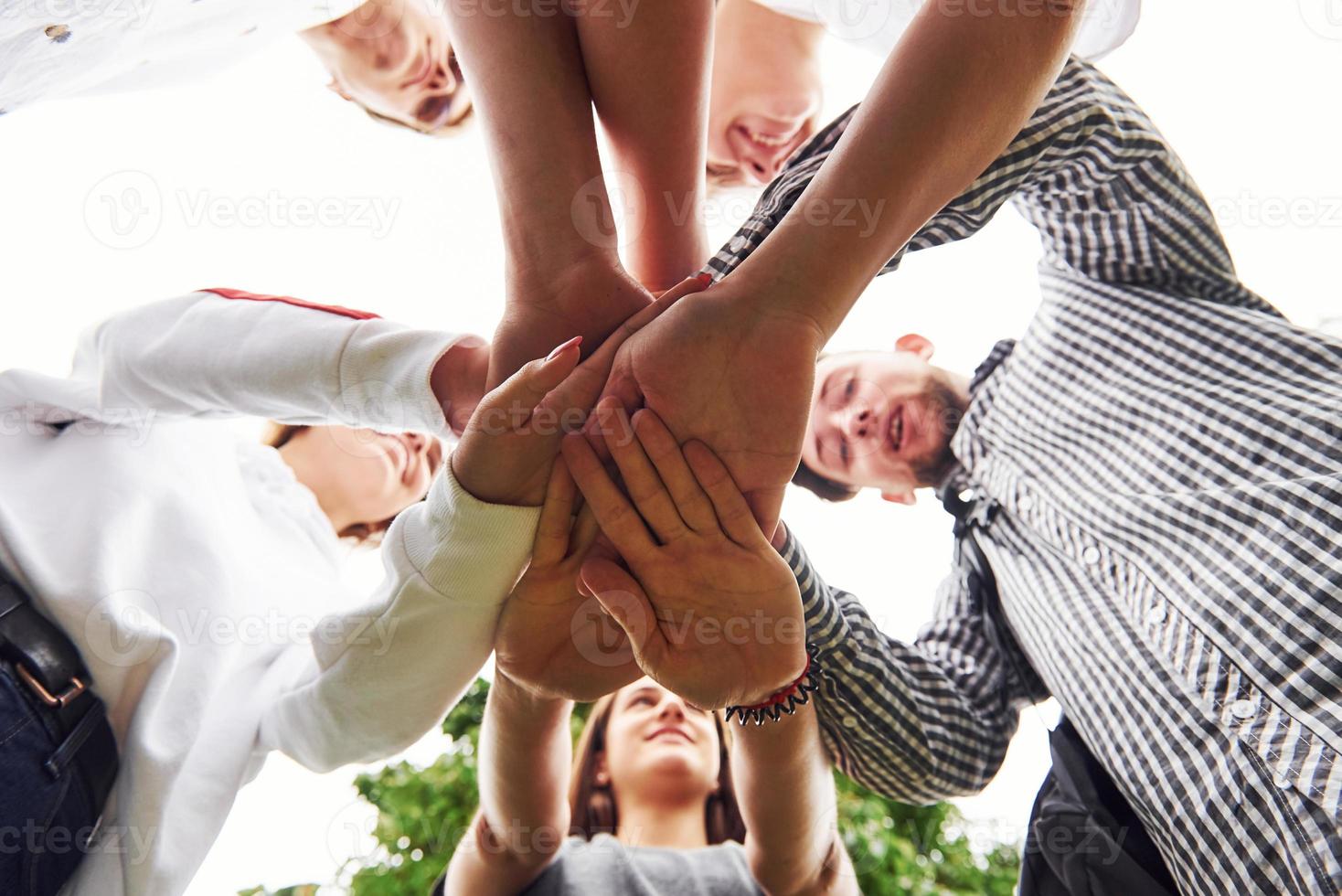 Close up view of hands of the young team of successful friends outdoors photo