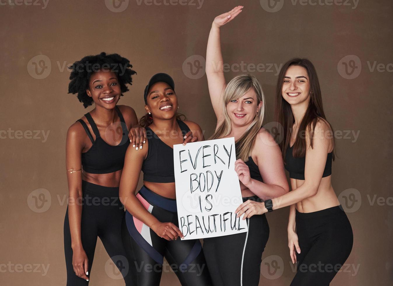 No complexes. Group of multi ethnic women standing in the studio against brown background photo