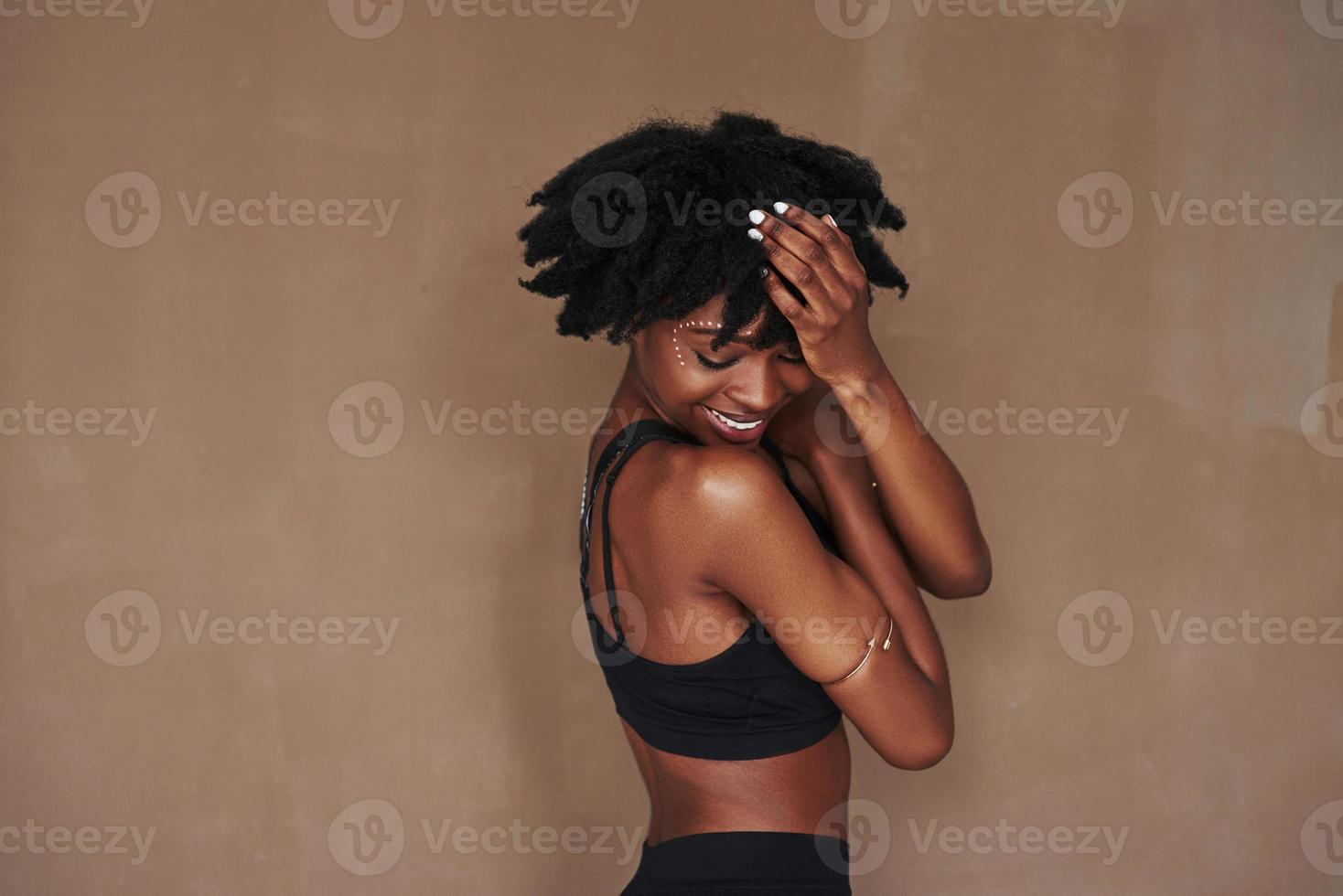 Satisfaction and positive emotions only. Young beautiful afro american woman in the studio against brown background photo