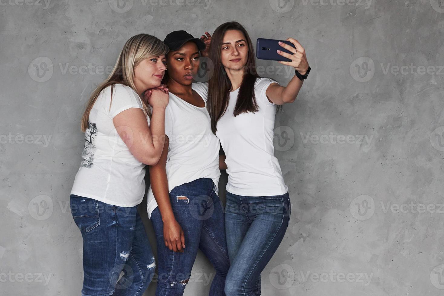 foto horizontal. grupo de mujeres multiétnicas de pie en el estudio con fondo gris