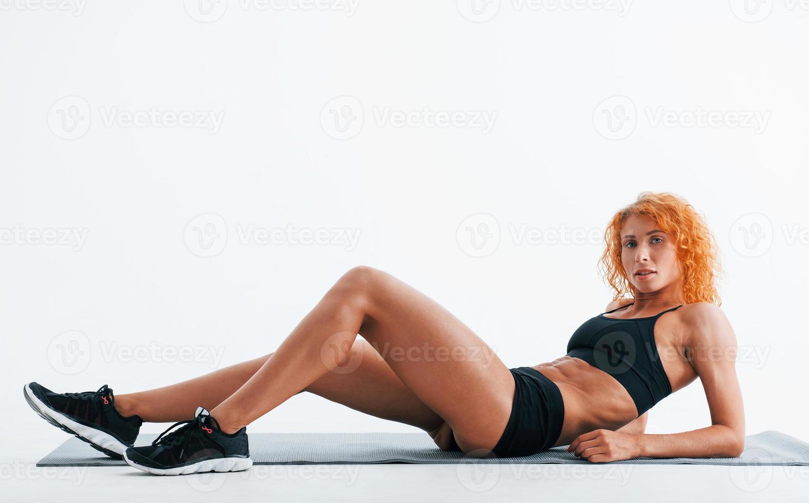 Rests on the roll mat. Redhead female bodybuilder is in the studio on white background photo