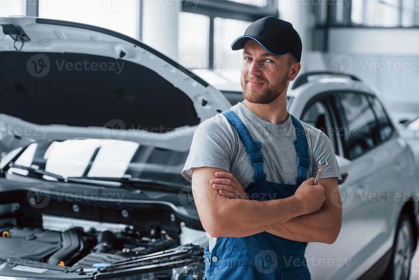 Lovely job. Employee in the blue colored uniform stands in the automobile salon photo