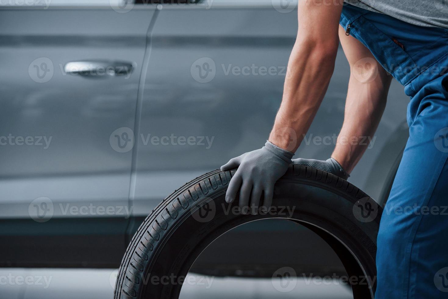 Replacement of winter and summer wheels. Mechanic holding a tire at the repair garage photo