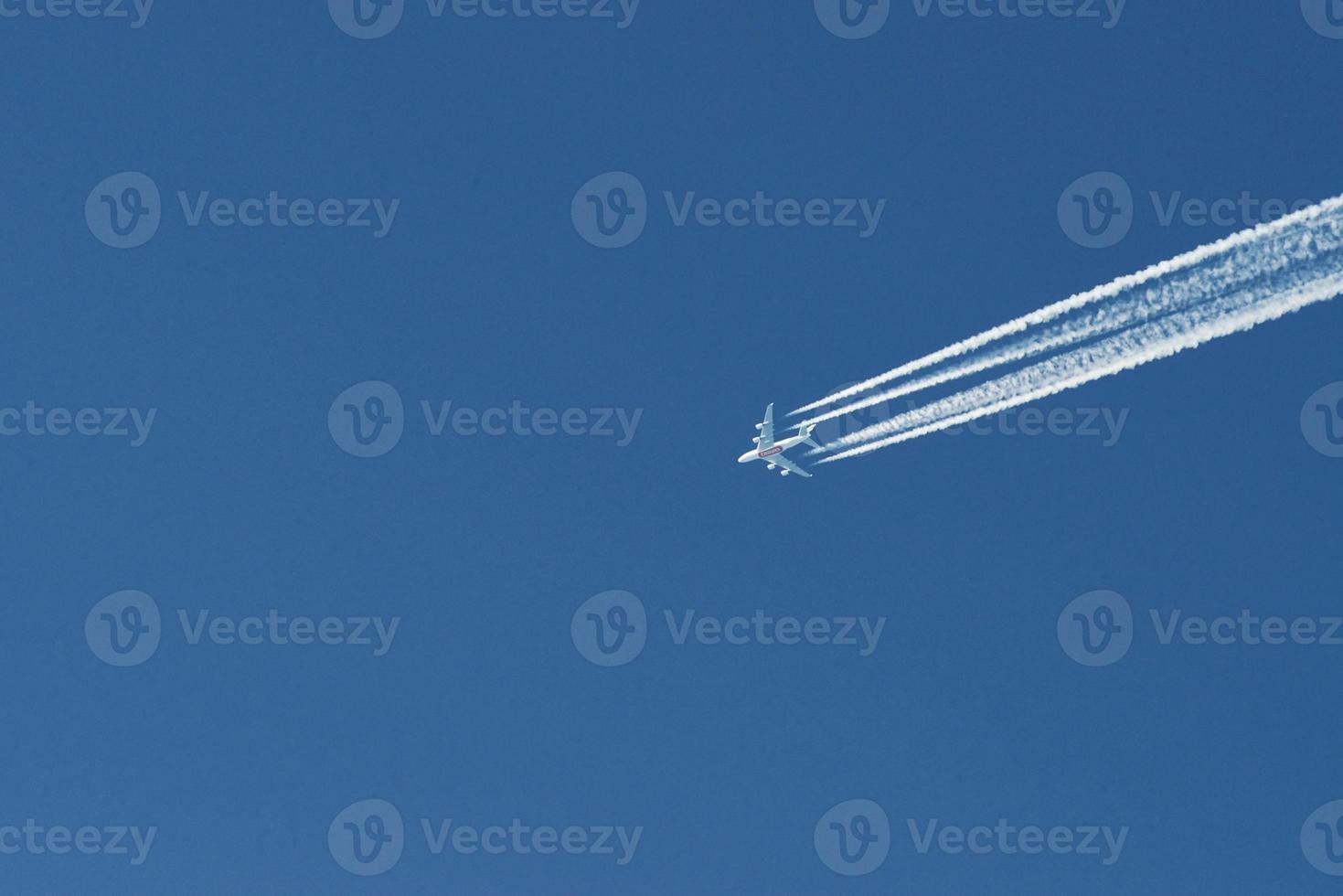 Modern plane flying high in the blue sky at sunny day. Speed and energy photo