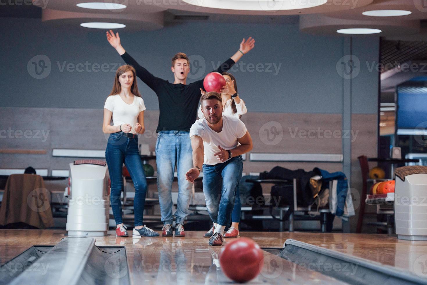 Good luck. Young cheerful friends have fun in bowling club at their weekends photo