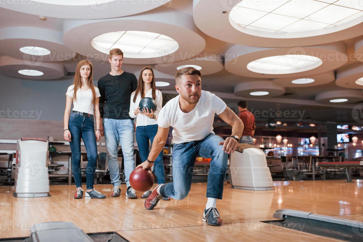 concentrado en el juego. jóvenes amigos alegres se divierten en el club de bolos los fines de semana foto