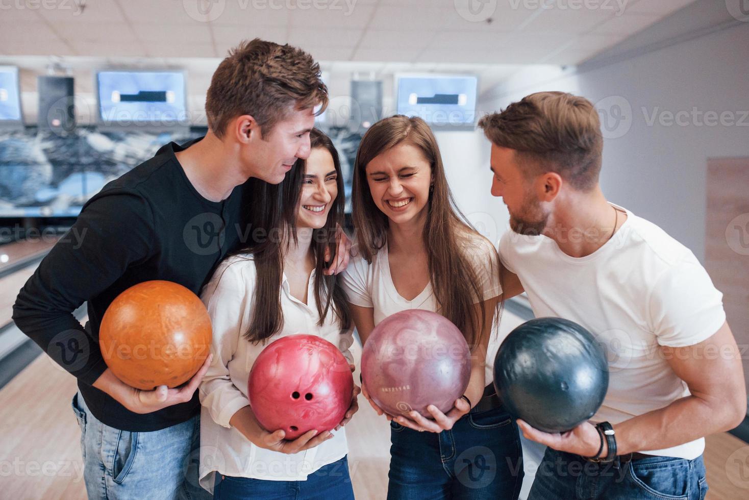Funny joke. Young cheerful friends have fun in bowling club at their weekends photo