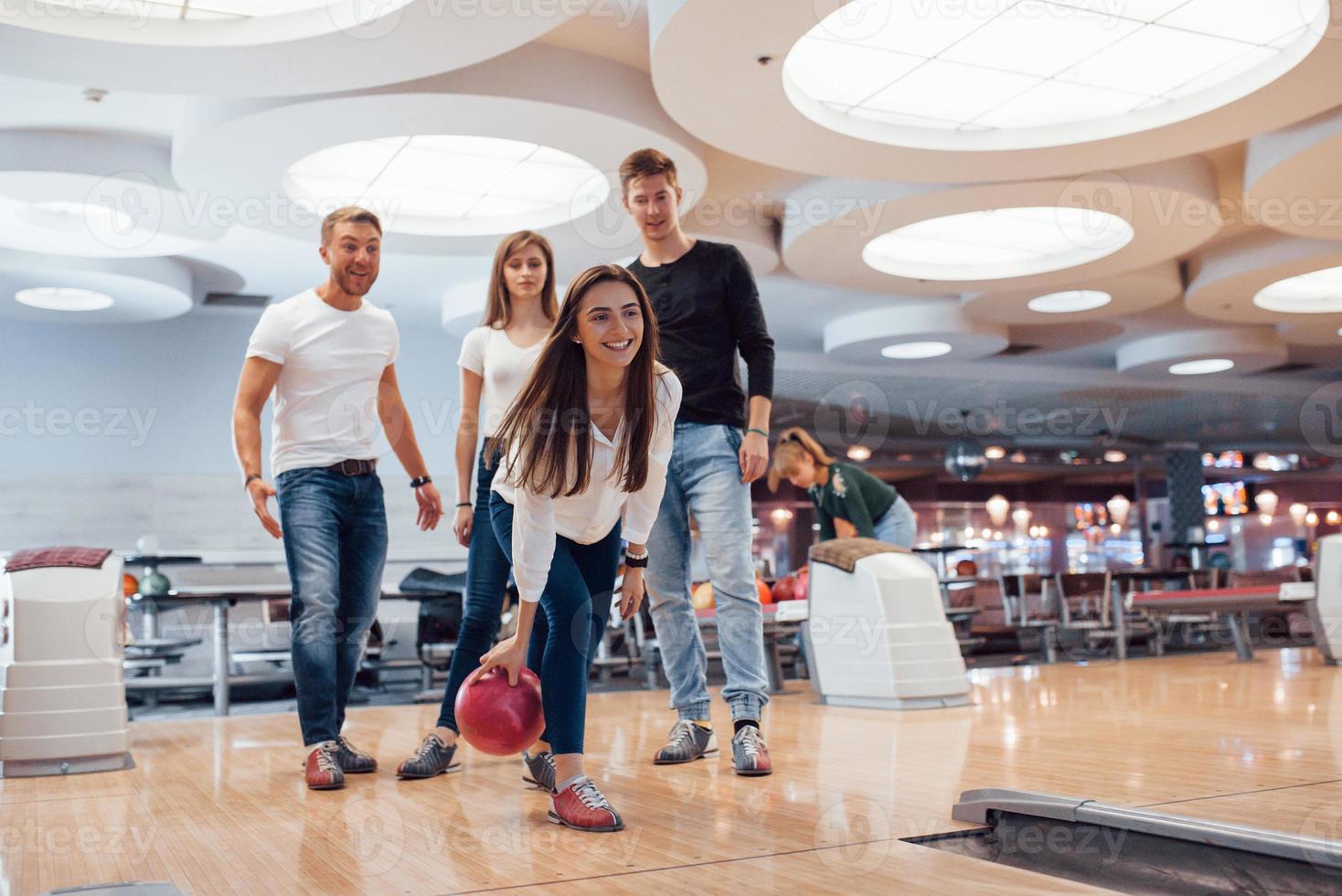 mirando hacia adelante. jóvenes amigos alegres se divierten en el club de bolos los fines de semana foto