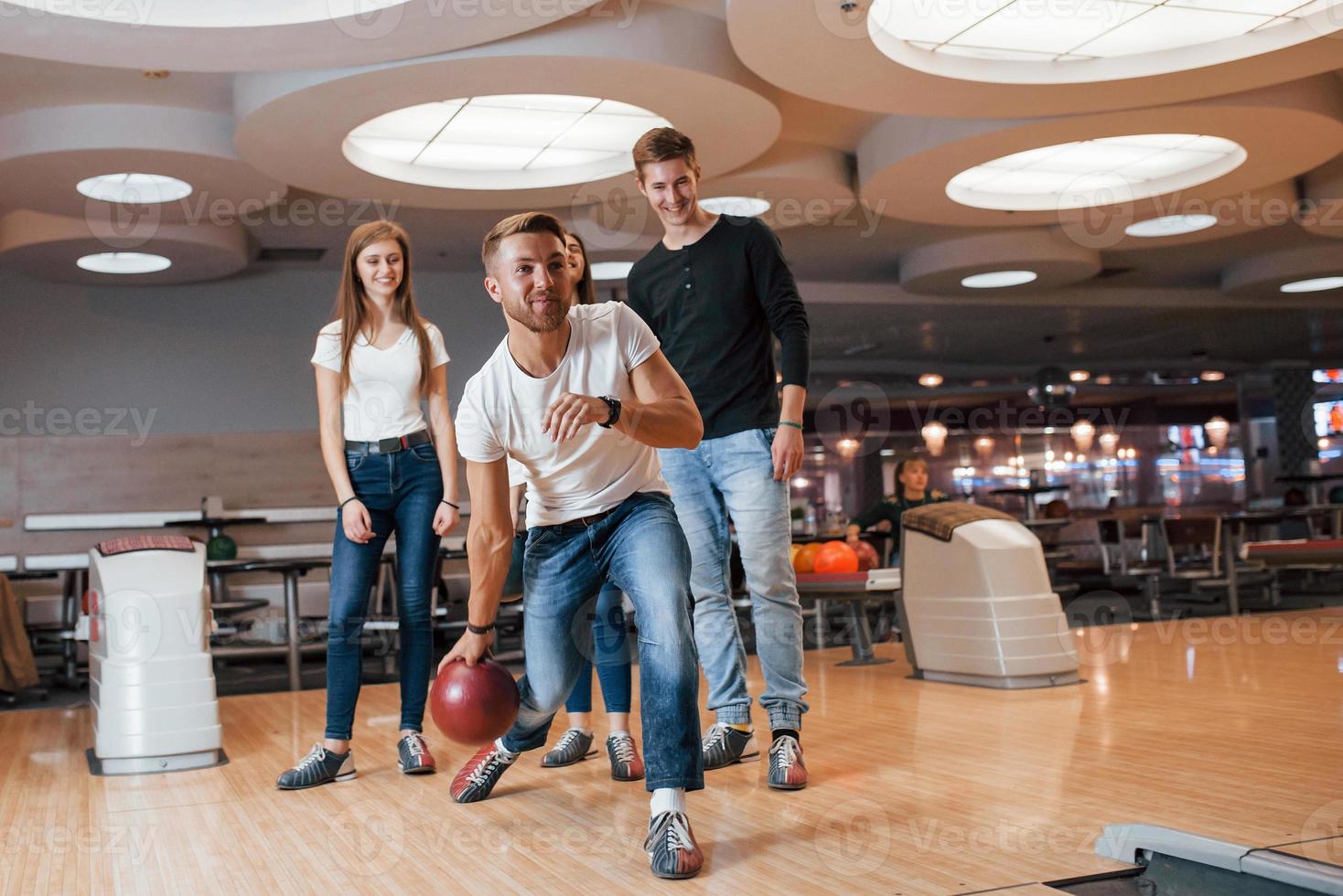 Here it goes. Young cheerful friends have fun in bowling club at their weekends photo