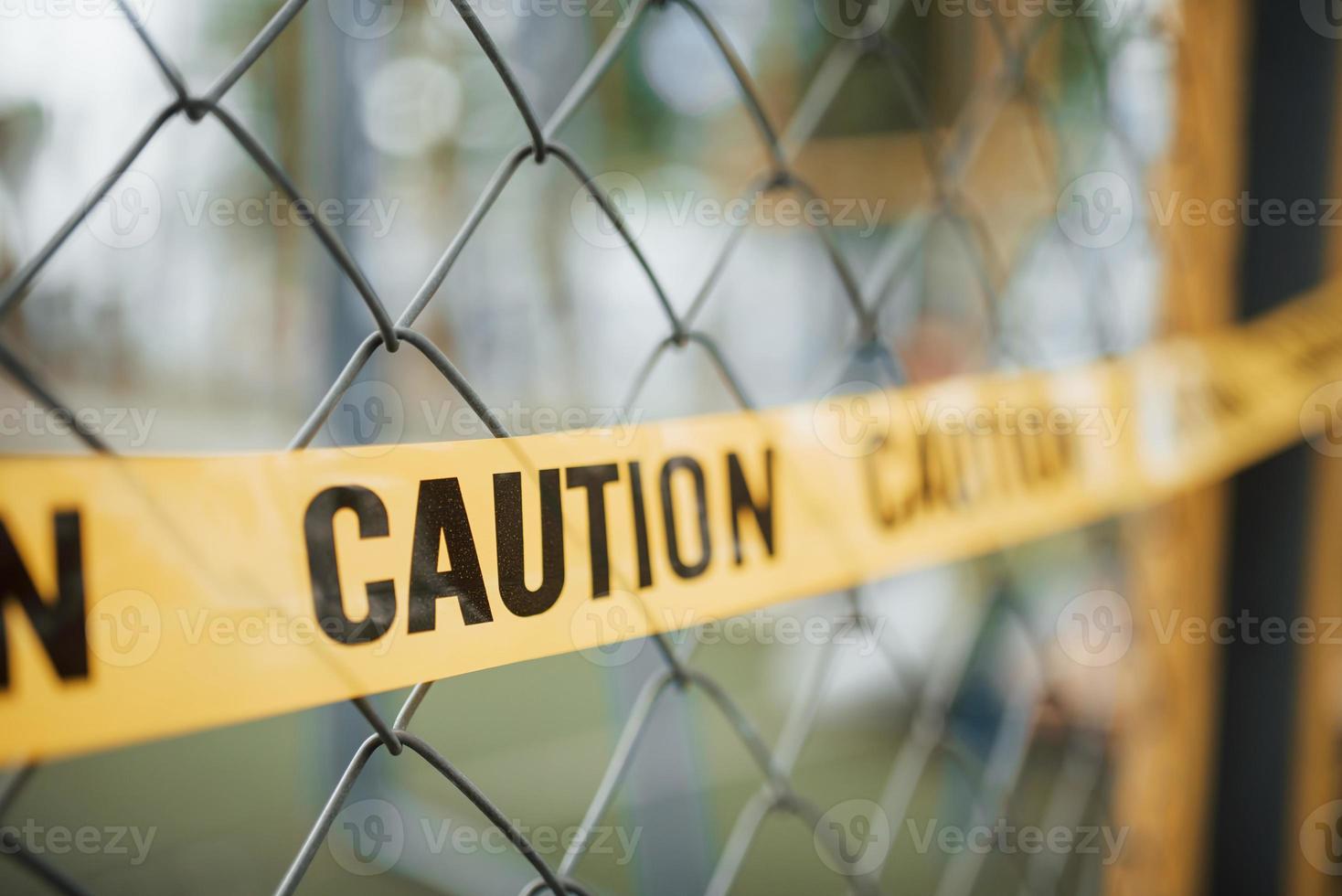 Do not enter. Yellow caution tape on the metal fence at daytime. Crime scene photo
