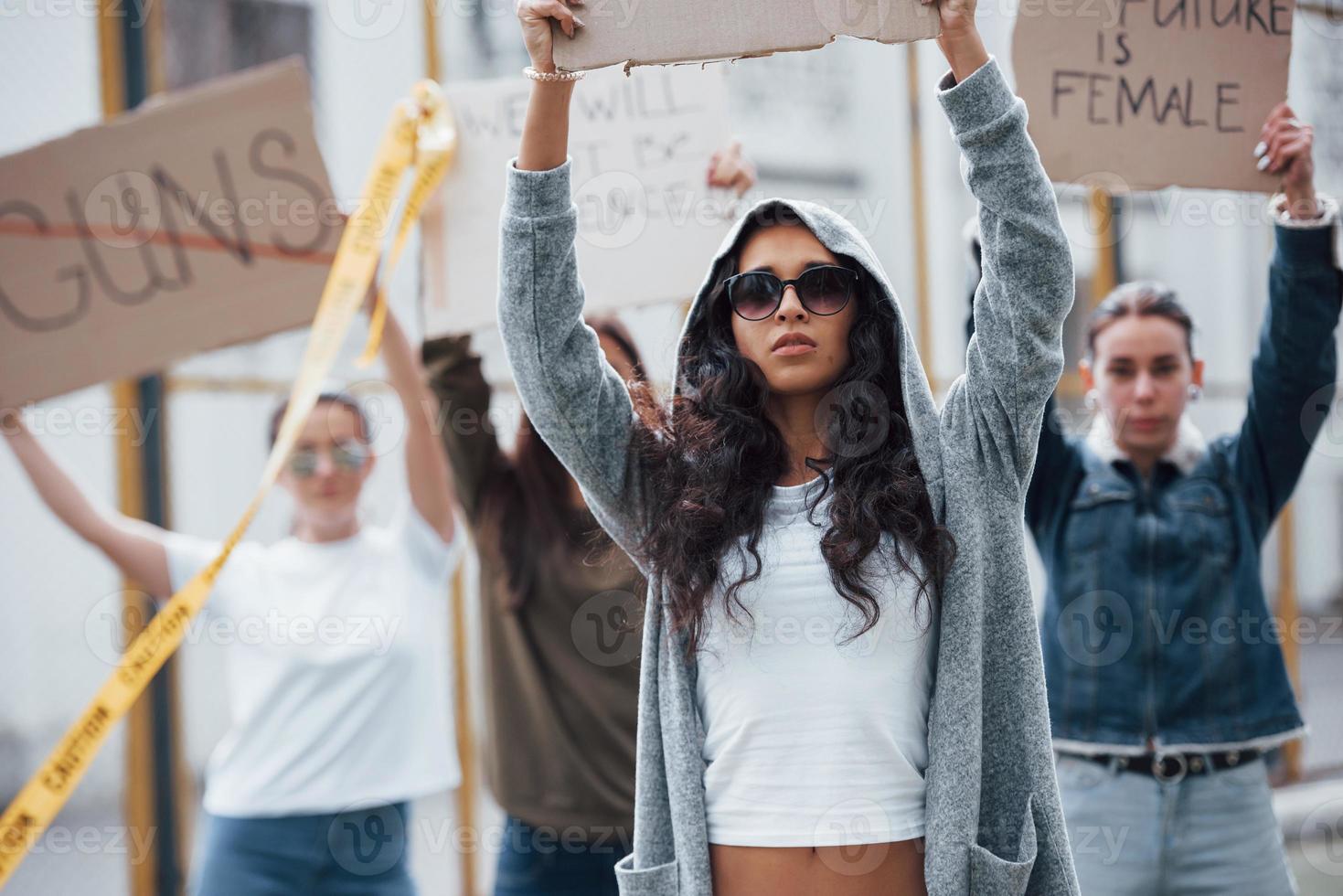 en gafas de sol y capucha. grupo de mujeres feministas tienen protesta por sus derechos al aire libre foto