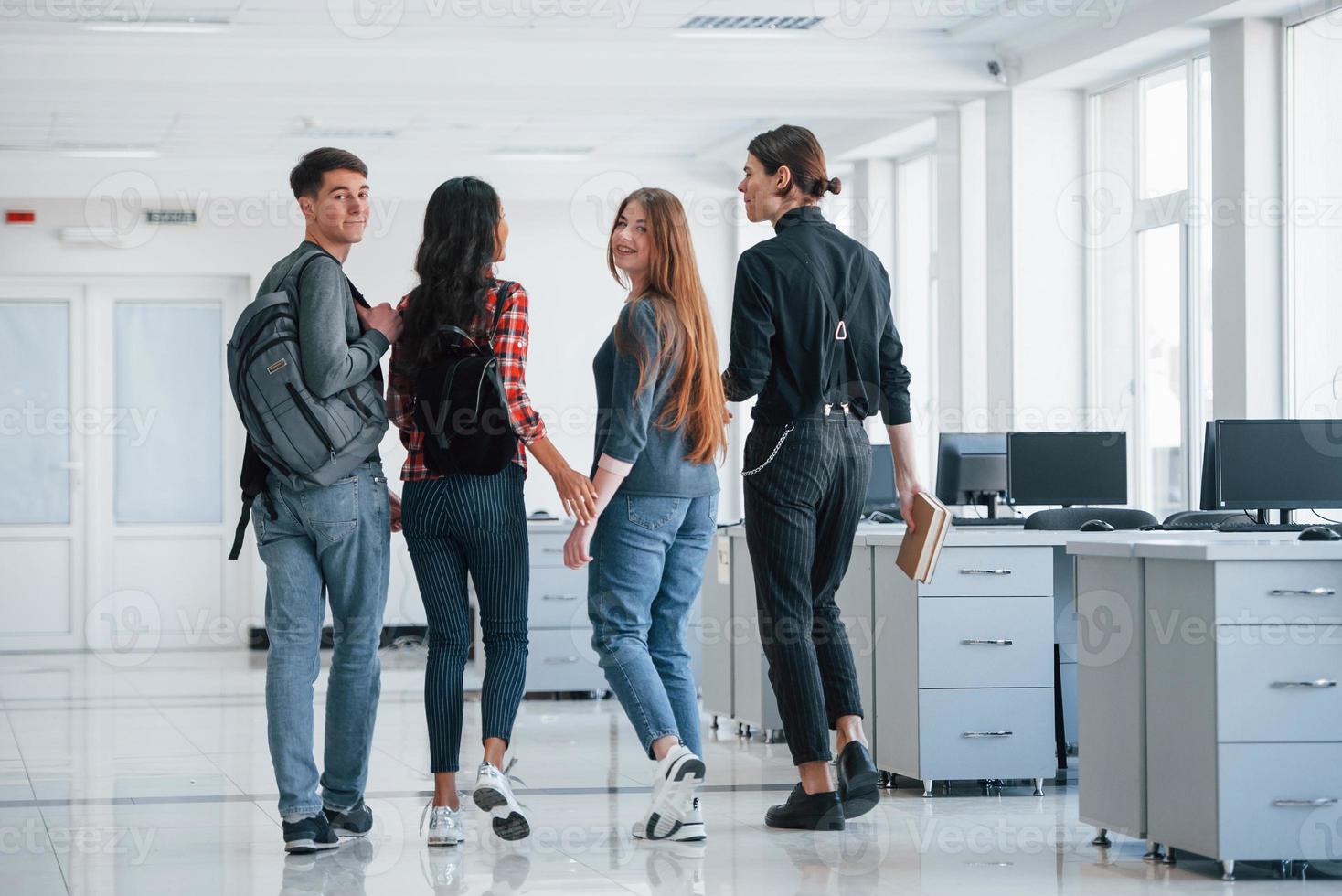 Turning back. Group of young people walking in the office at their break time photo