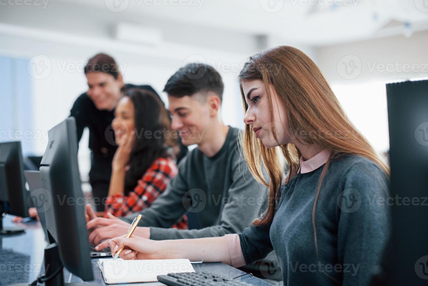 Concentrated blonde. Group of young people in casual clothes working in the modern office photo