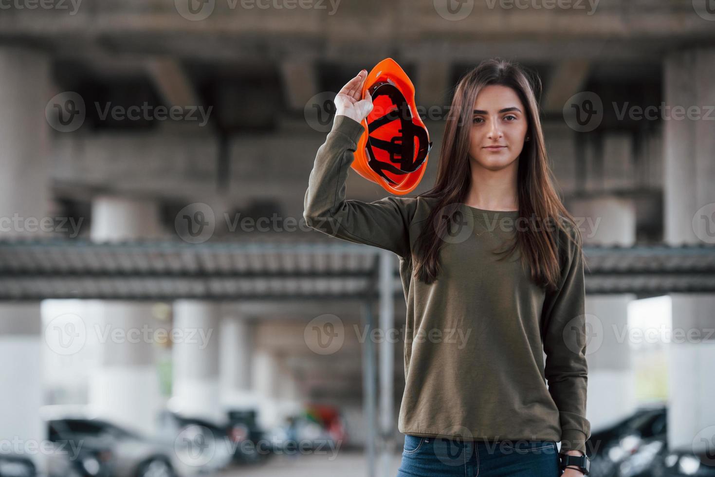 quitándose el sombrero. retrato de una hermosa joven con casco de seguridad parado debajo del puente foto