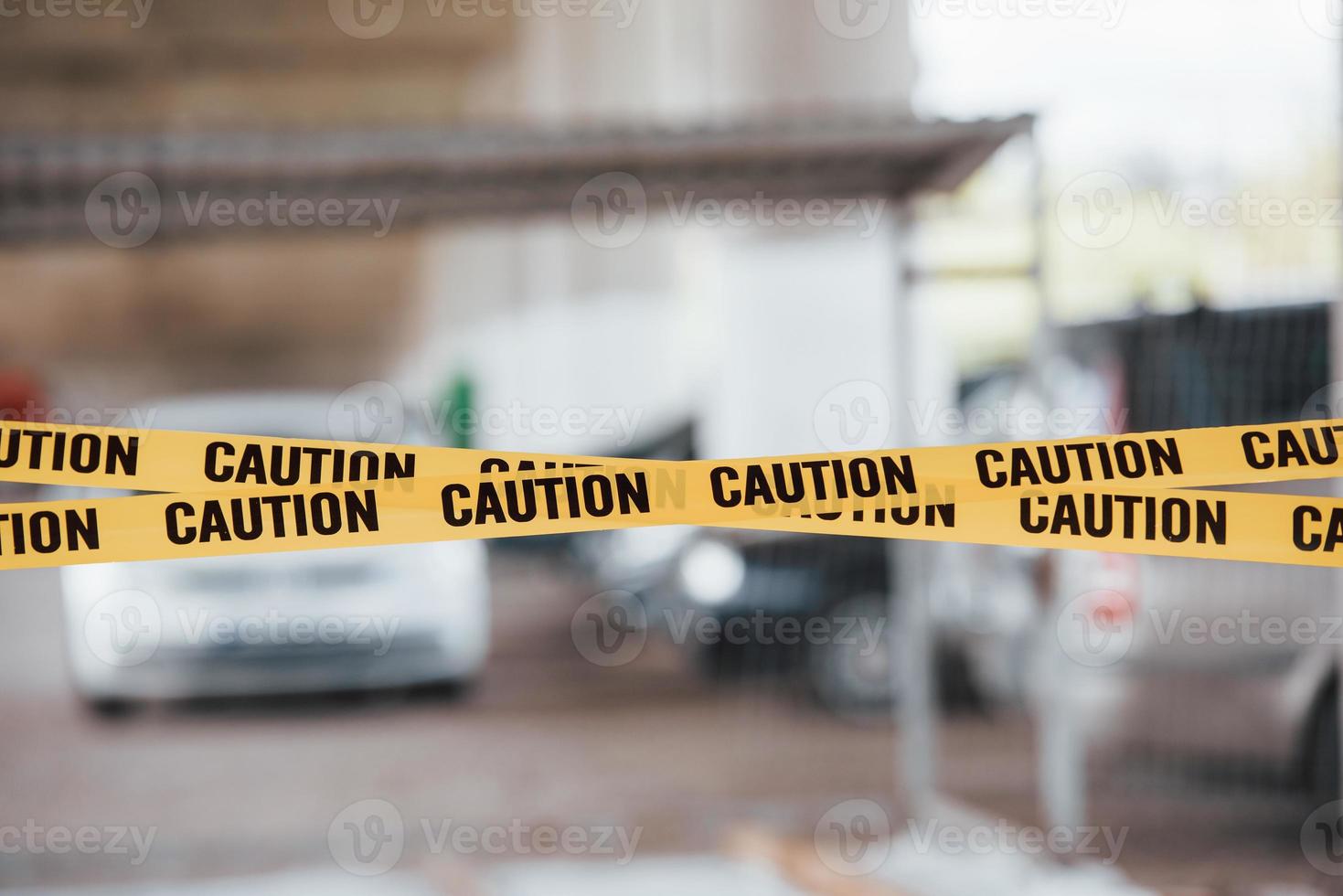 Blurred background. Yellow caution tape near the car parking lot at daytime. Crime scene photo