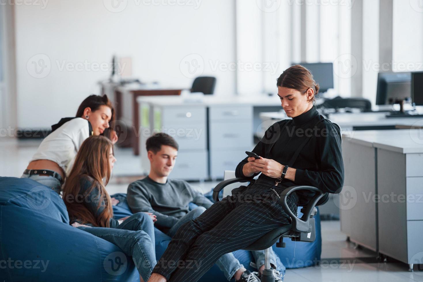Wireless technologies. Group of young people in casual clothes working in the modern office photo