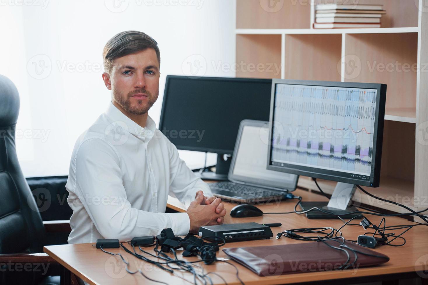 White shirt and many of devices. Polygraph examiner works in the office with his lie detector's equipment photo