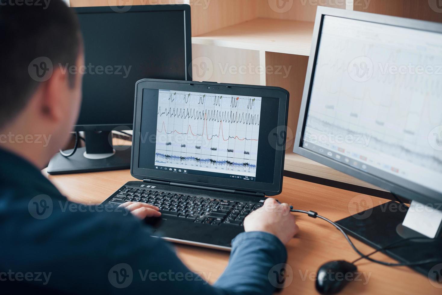 Analizying information. Polygraph examiner works in the office with his lie detector's equipment photo