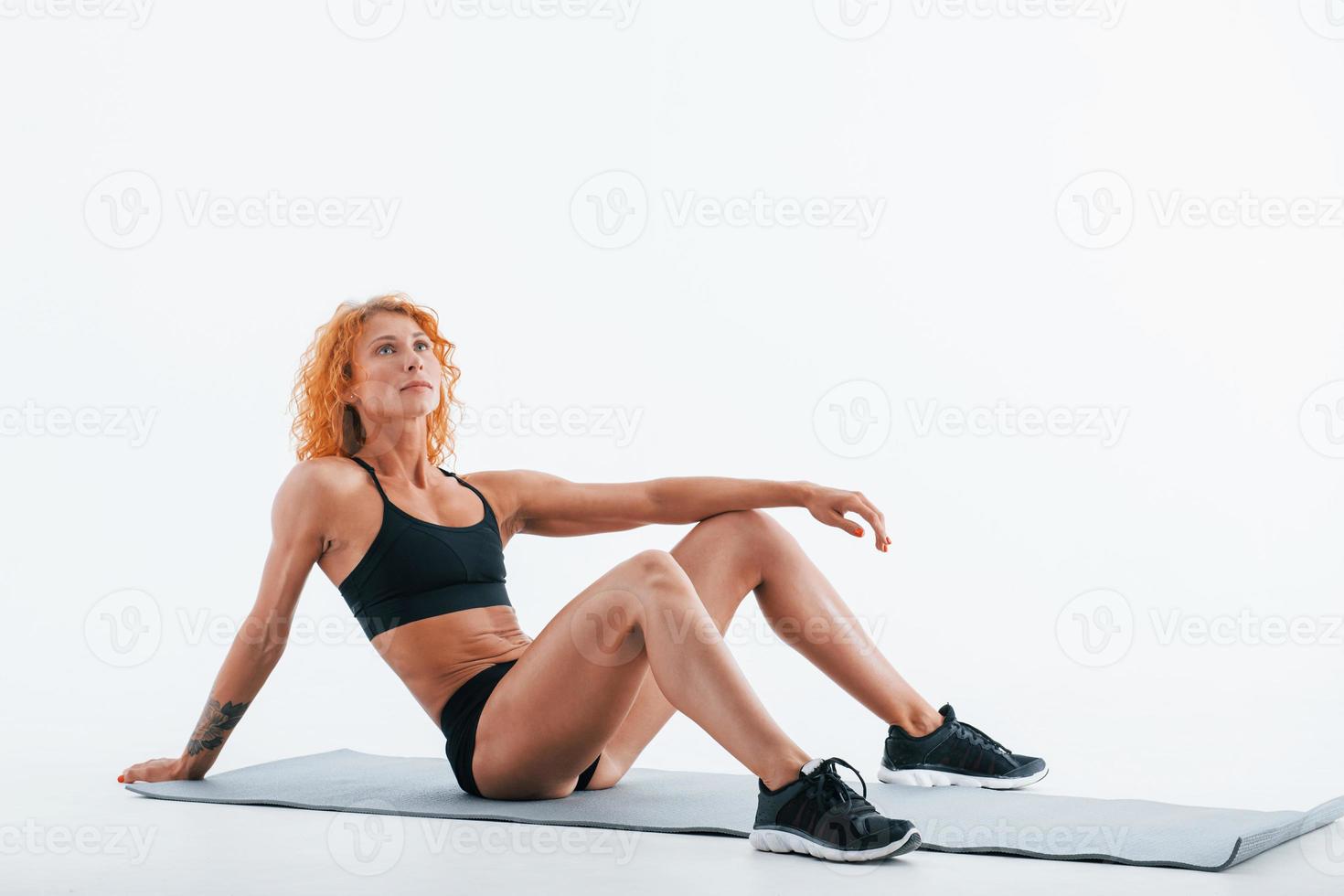 Rests on the roll mat. Redhead female bodybuilder is in the studio on white background photo