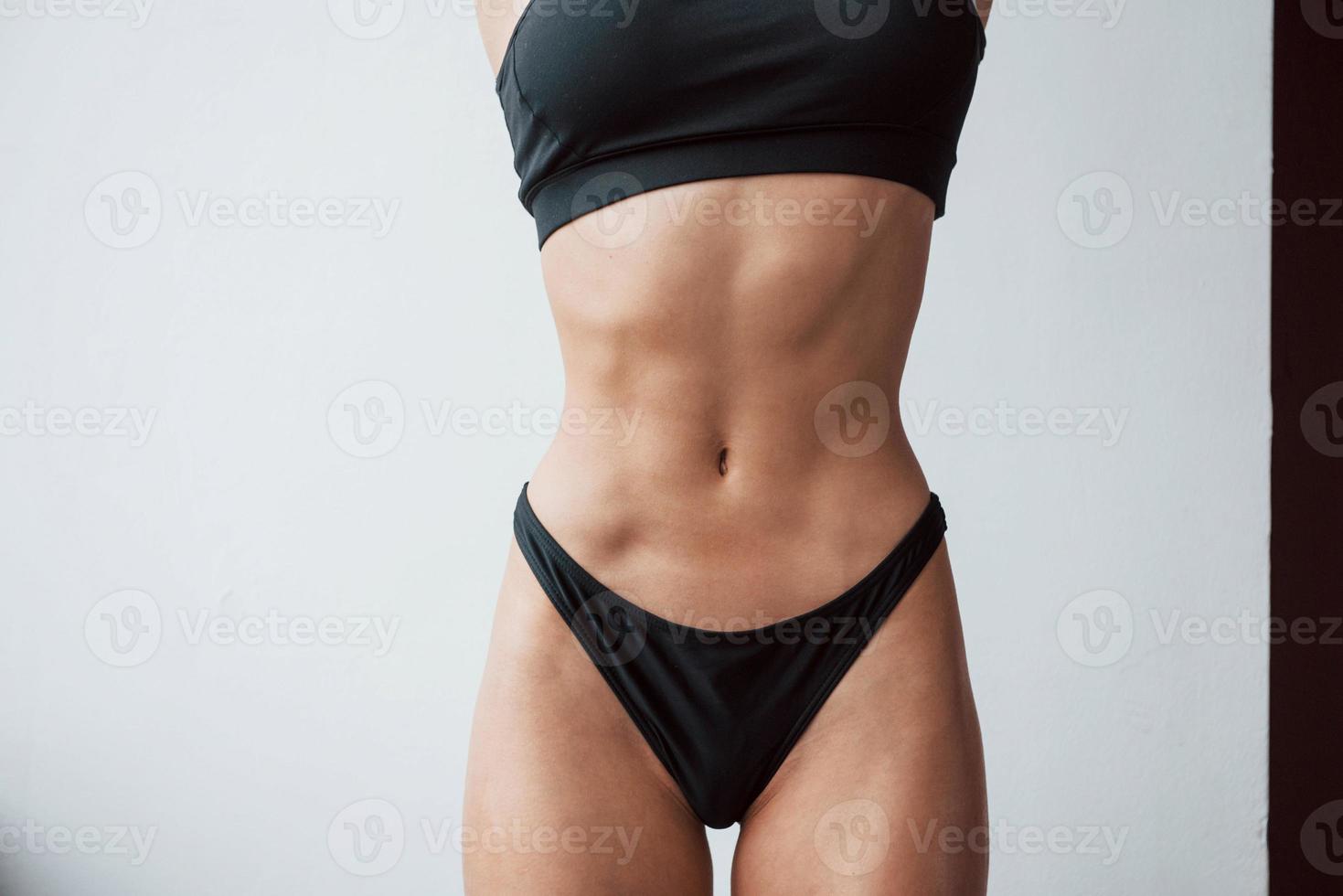 Cropped photo. Particle view of hot slim body type of girl that stands in the room photo