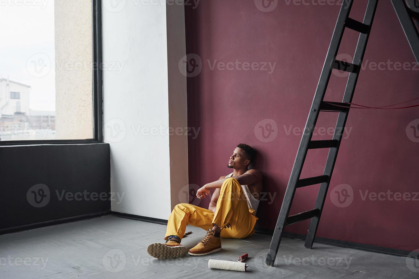 Looking through the window. Young african american worker in the yellow uniform have some job photo