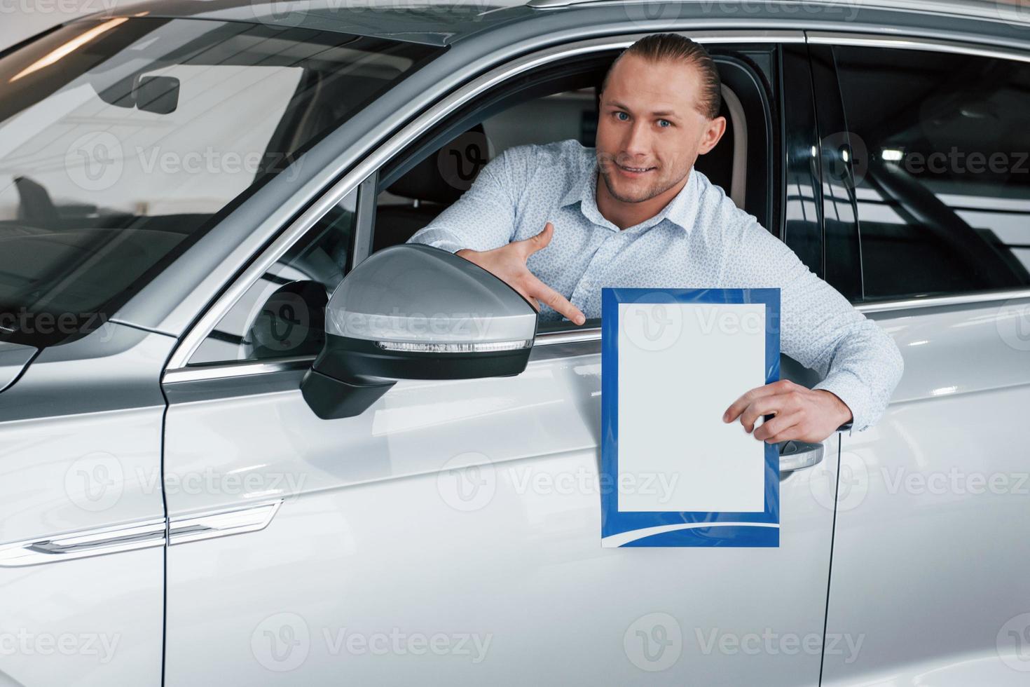 Conception of business. Manager sitting in modern white car with paper and documents in hands photo