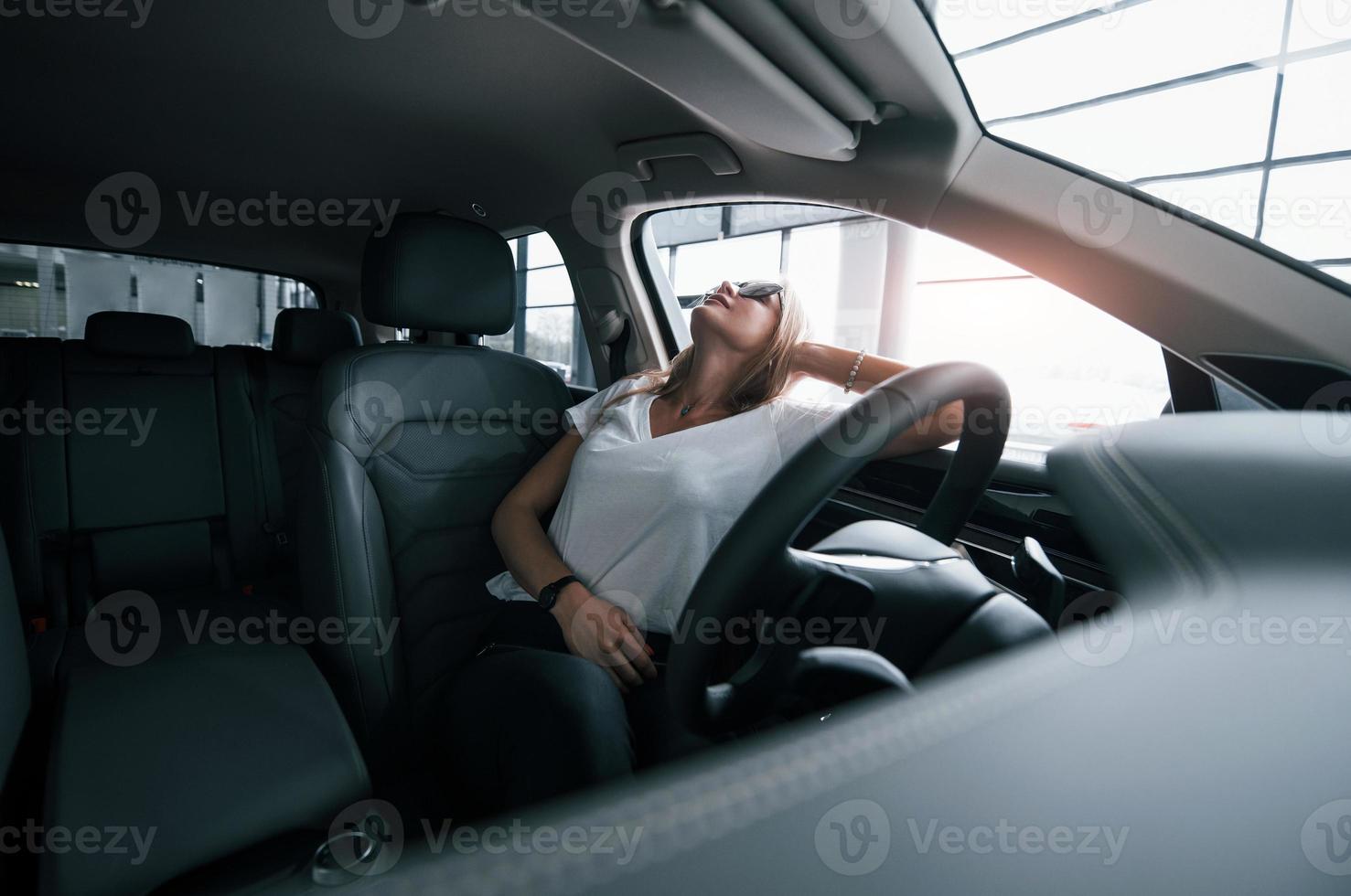 Enjoying comfortable interior. Girl in modern car in the salon. At daytime indoors. Buying new vehicle photo