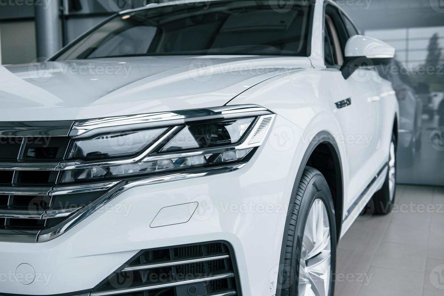 Brand new auto. Particle view of modern luxury white car parked indoors at daytime photo