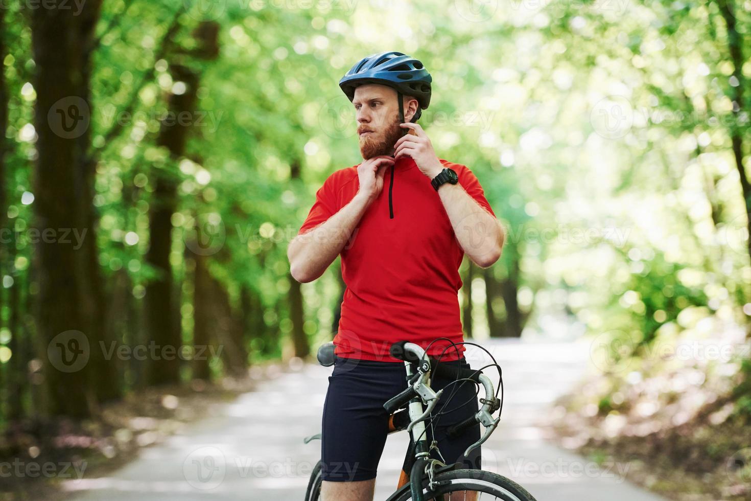 Almost on the finish point. Cyclist on a bike is on the asphalt road in the forest at sunny day photo