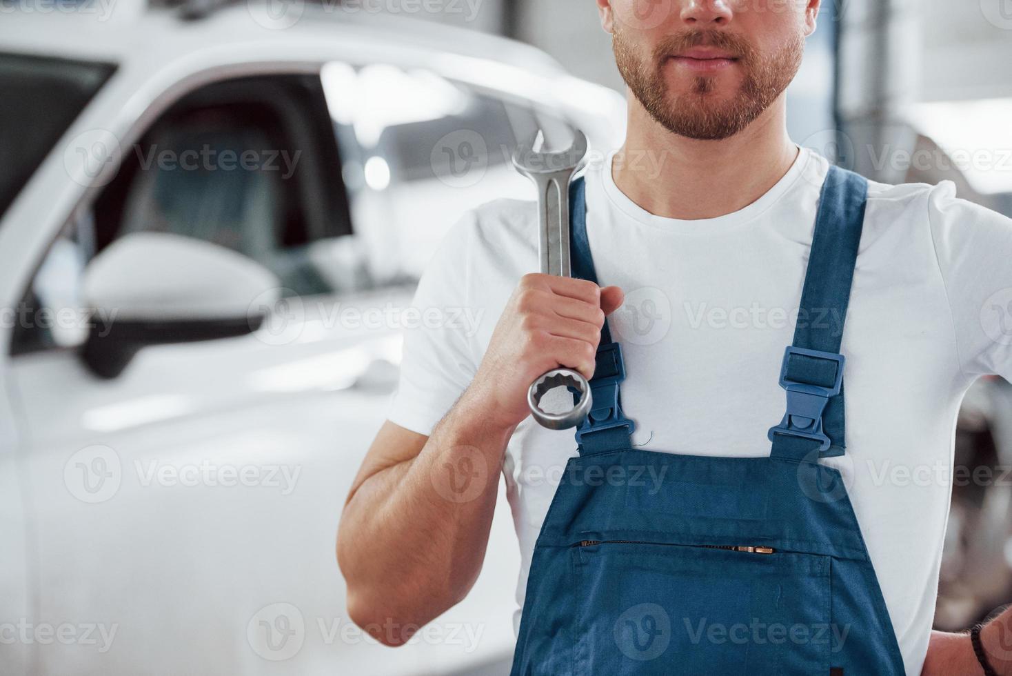 Man with light beard. Employee in the blue colored uniform works in the automobile salon photo