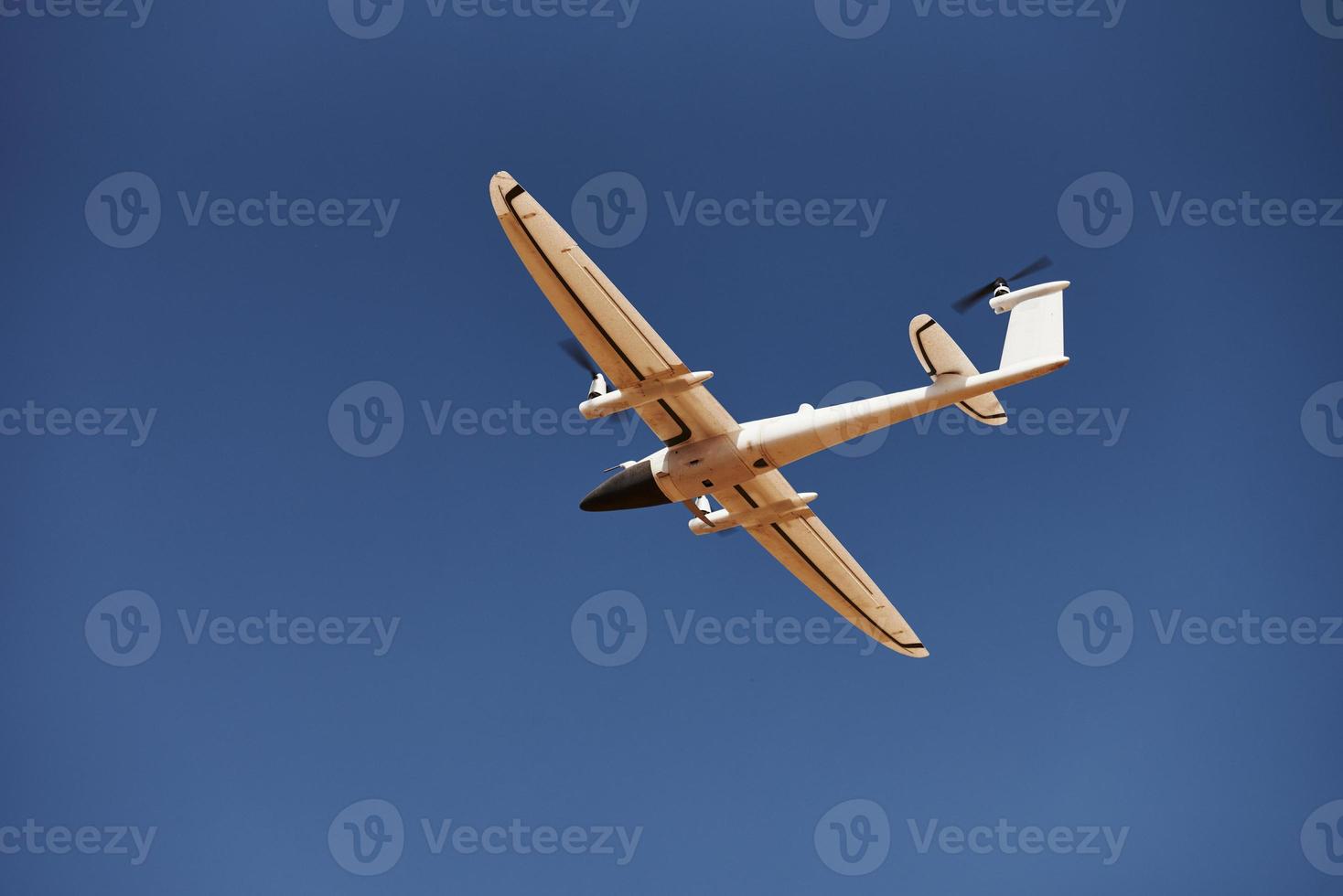 Modern small remote controlled white colored plane flying up in the sky photo